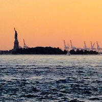 The Statue of Liberty at sunset flanked by construction cranes reminds us that the monument is a symbol of our historical role as refuge for immigrants and chief exporter of freedom. w